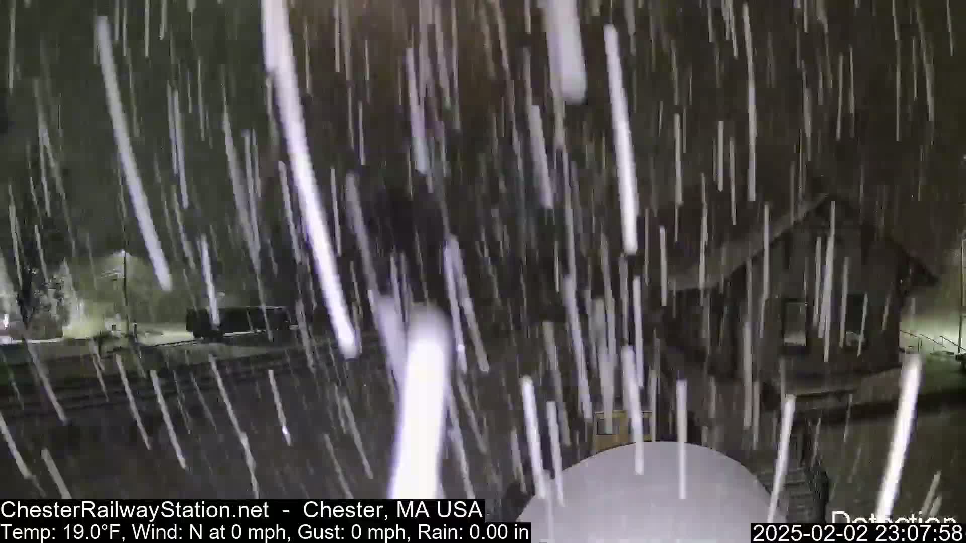 Heavy snowfall at night obscures a building and surrounding area.