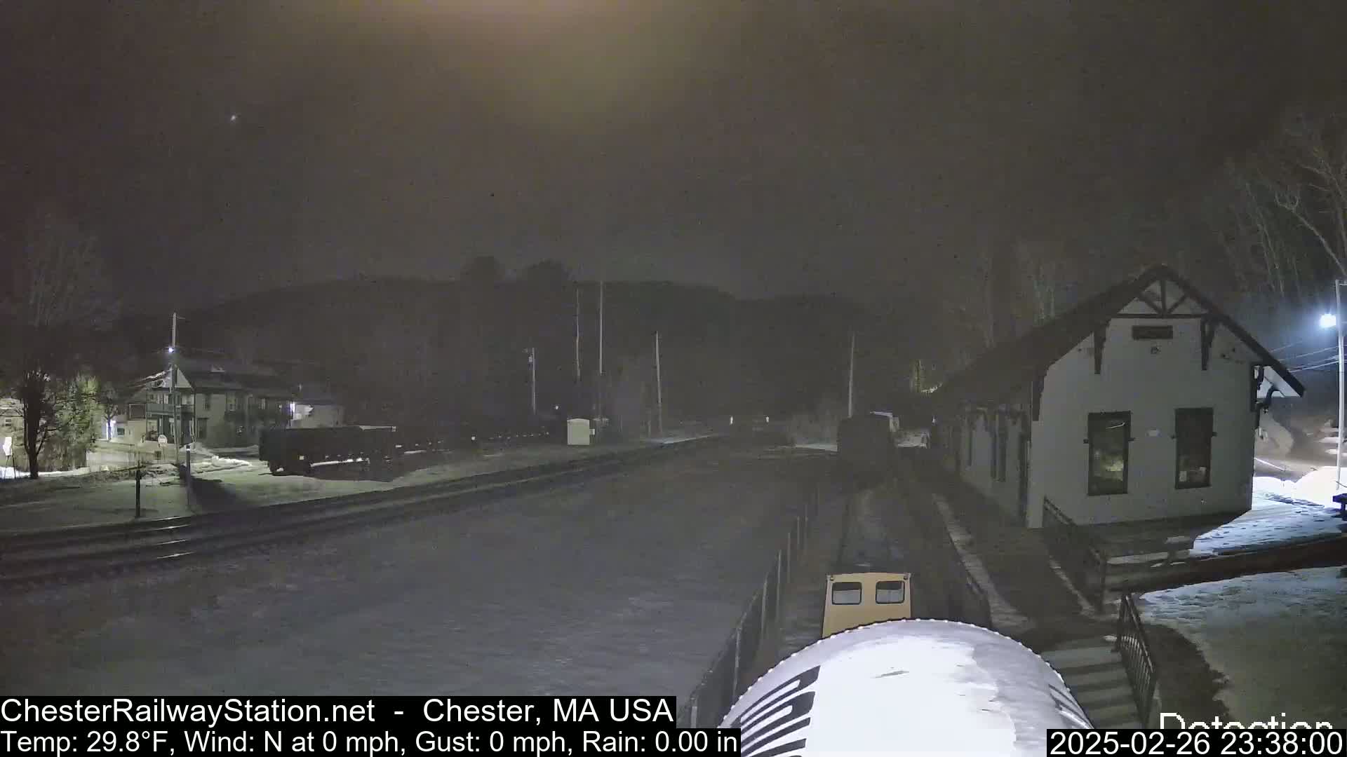 A nighttime snow-covered train station and railway yard are visible under a dark sky.