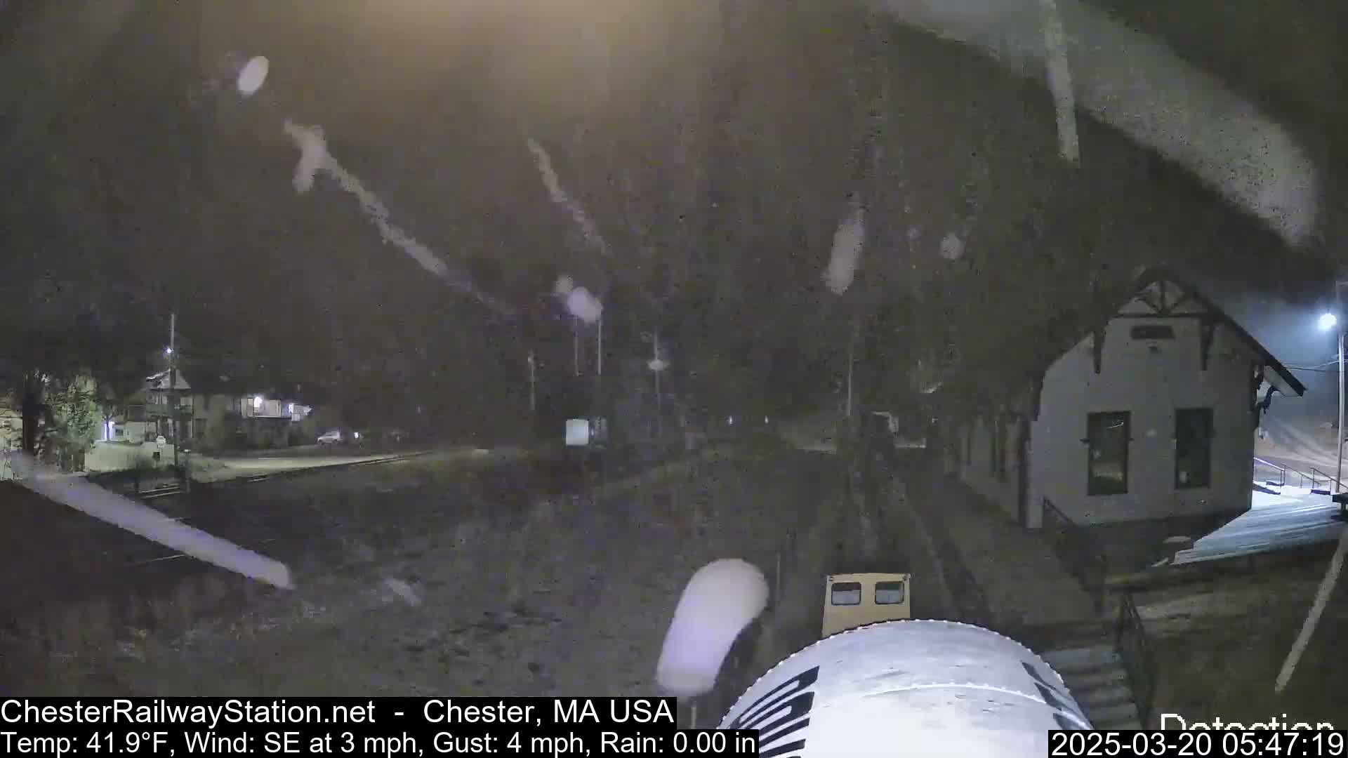 A nighttime scene of a train station in the rain, with a southeast wind at 3 mph and gusts up to 4 mph.