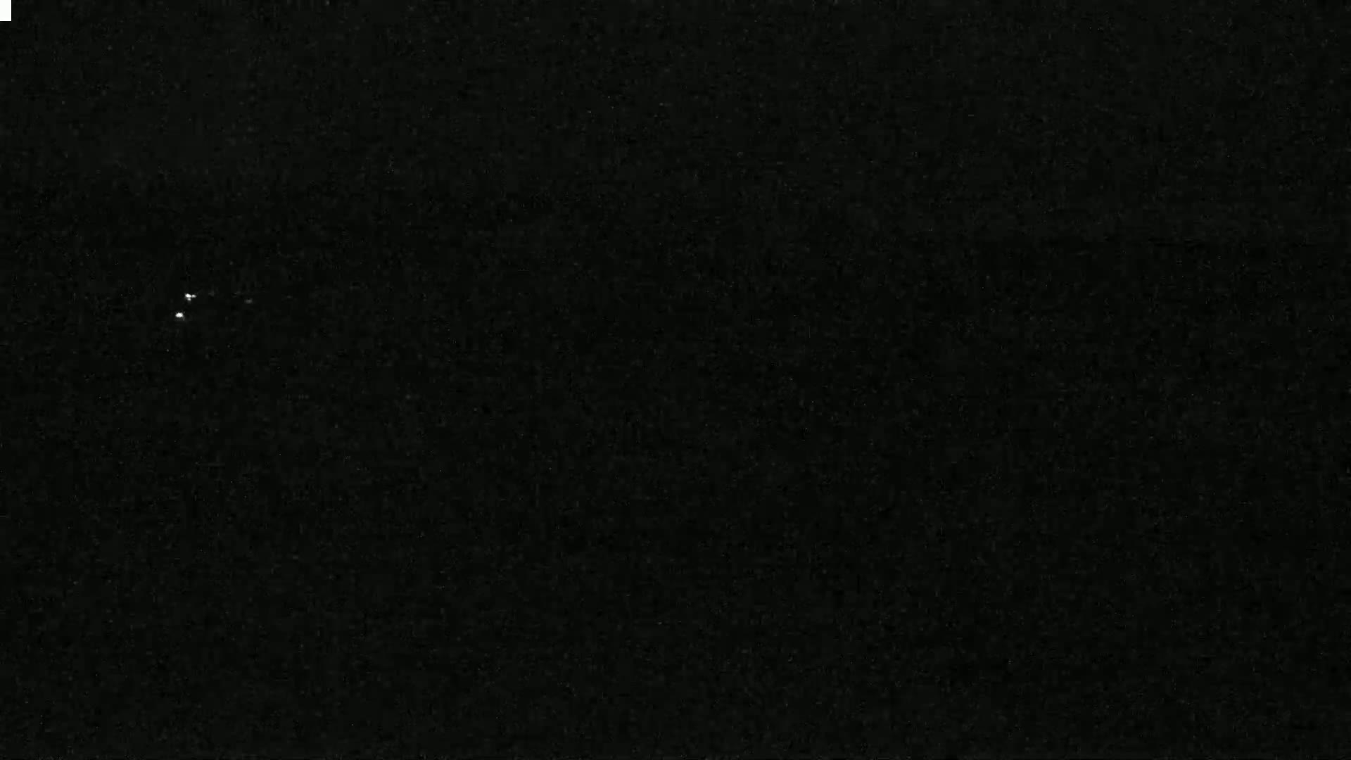 A dark, nighttime scene shows two small, bright lights in the distance.