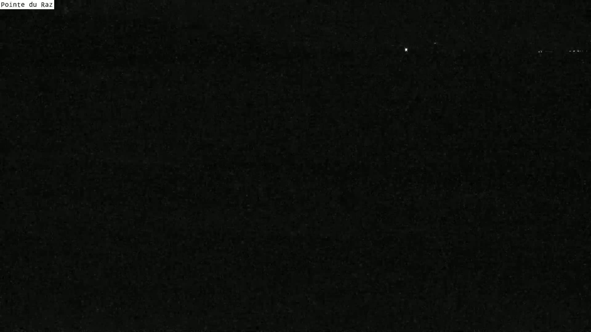 A very dark, possibly nighttime image shows a few distant, faint lights on the horizon.