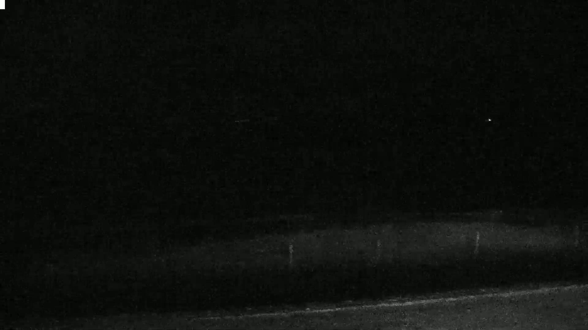 A dark, nighttime scene shows a road and a distant, barely visible landscape under a clear, starlit sky.