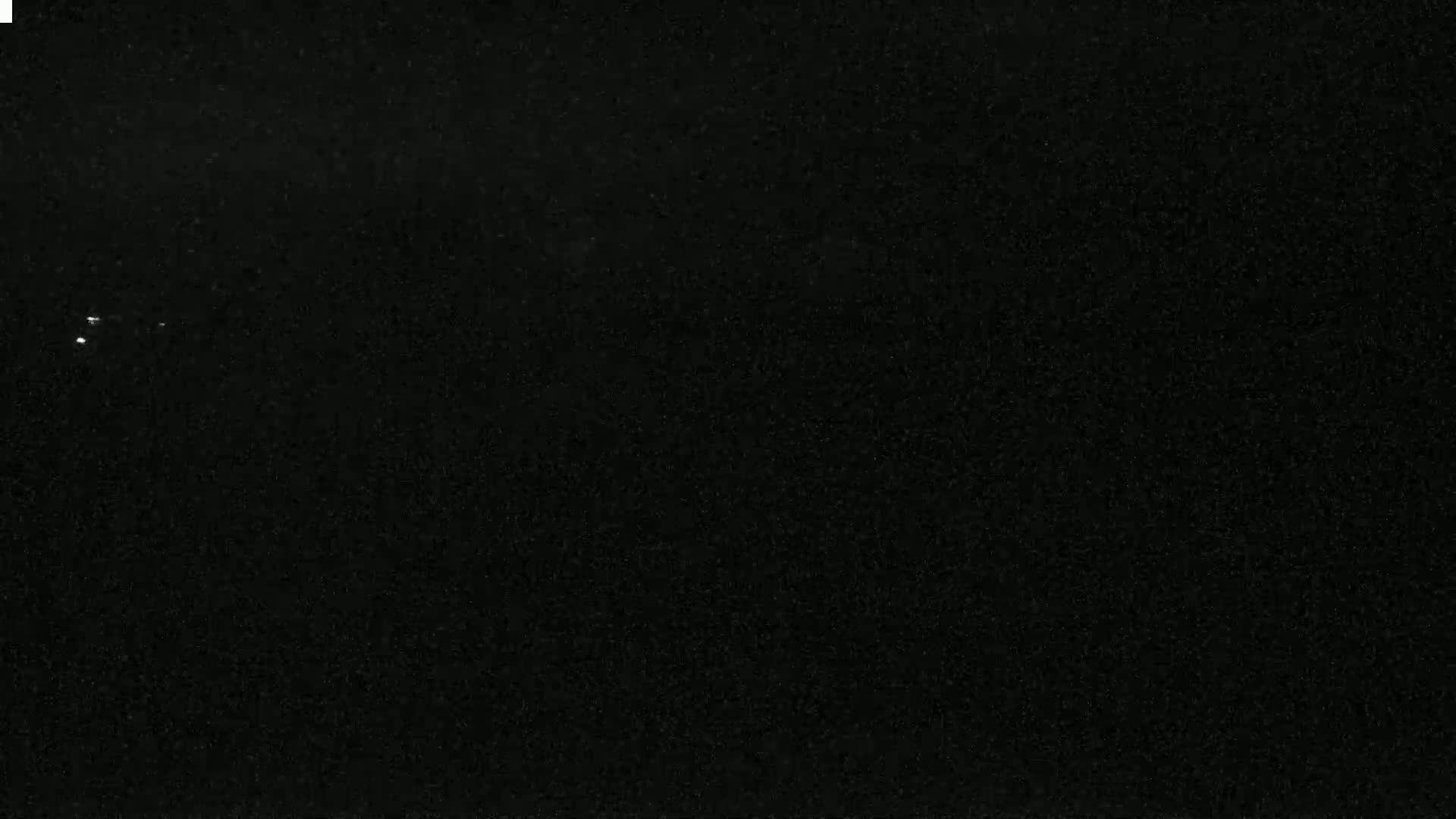 The image shows a dark, possibly nighttime, sky with a few faint, distant lights.