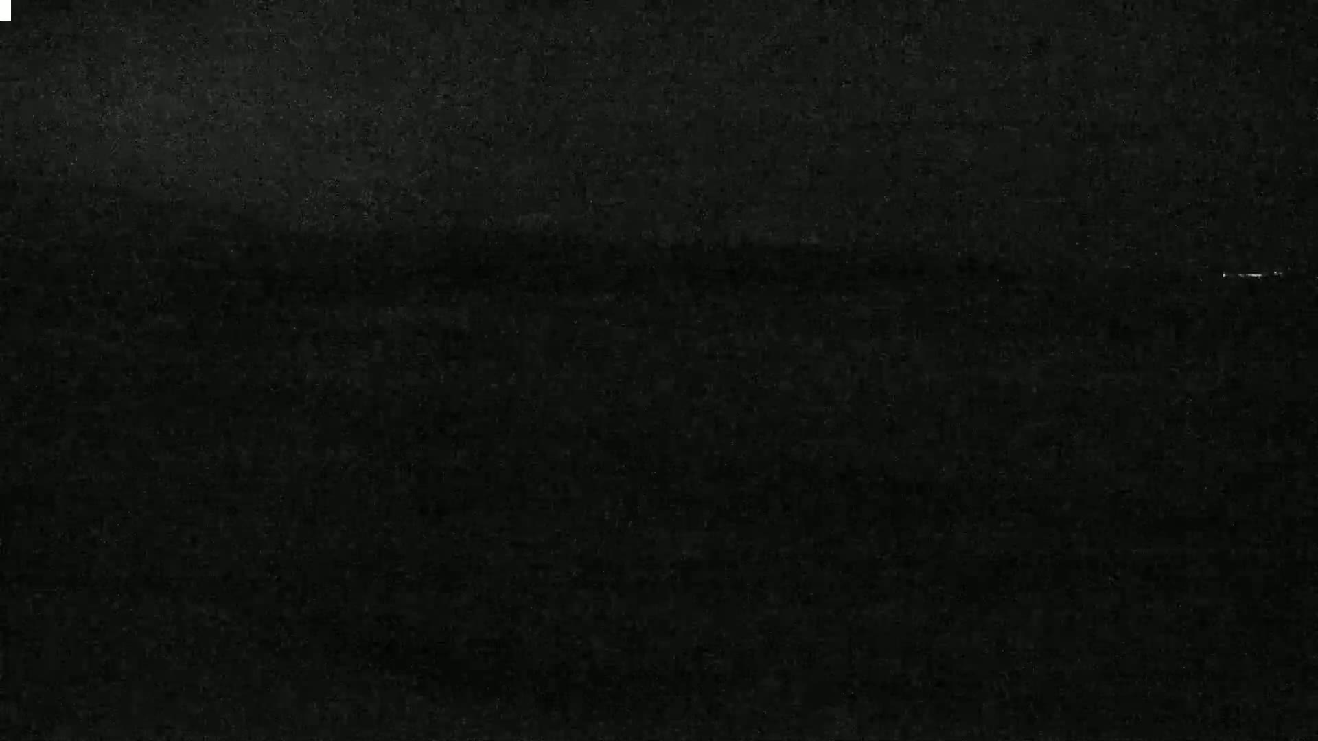 A dark, grainy image shows a mostly black scene with a faint, lighter horizontal line near the center.