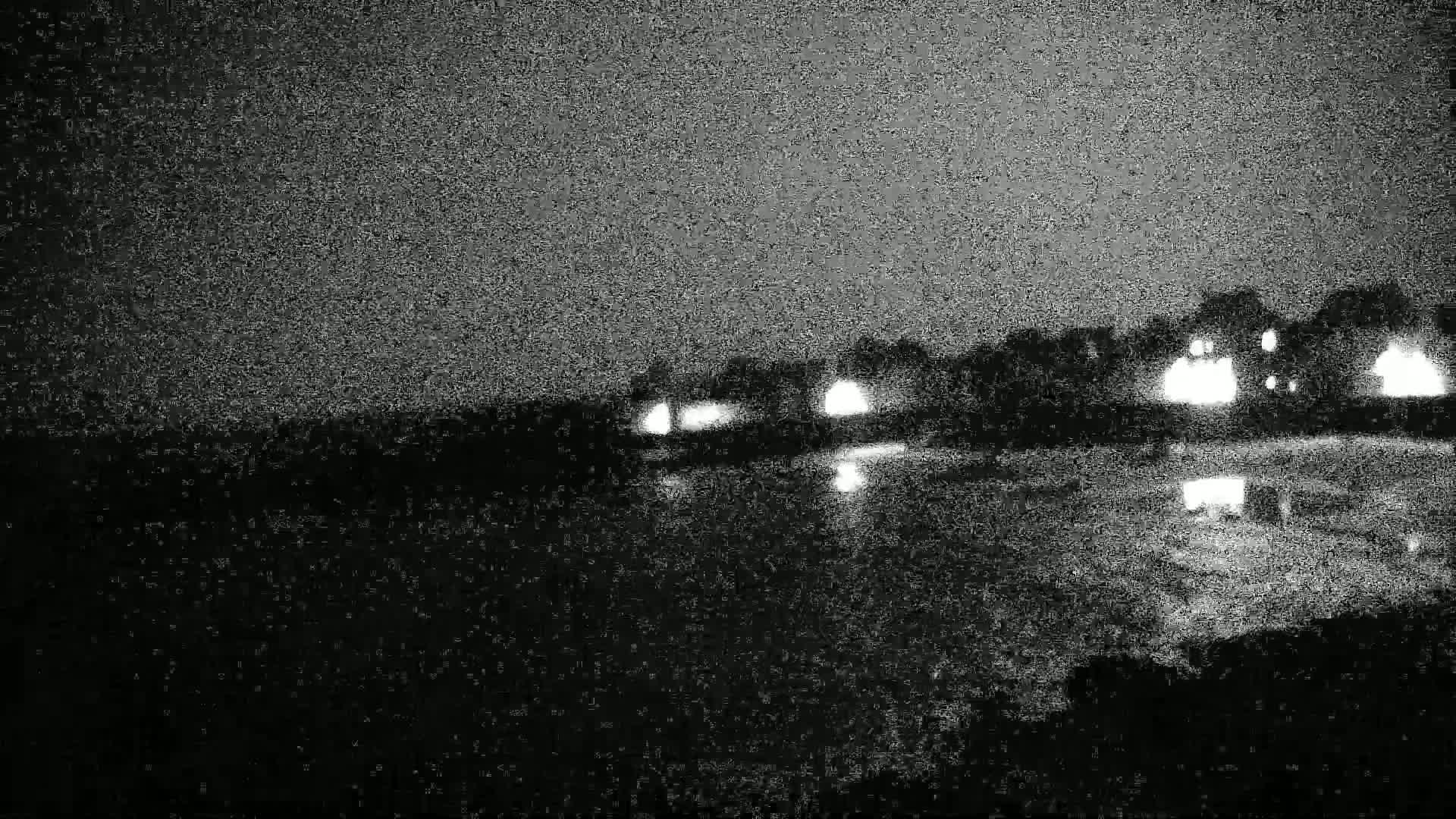 At night, dimly lit buildings are reflected in dark, still water.