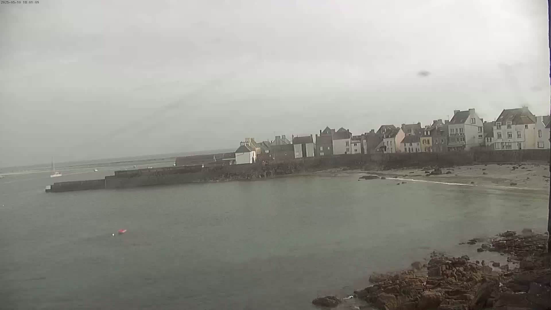 A row of buildings sits along a calm, grey body of water on an overcast day.