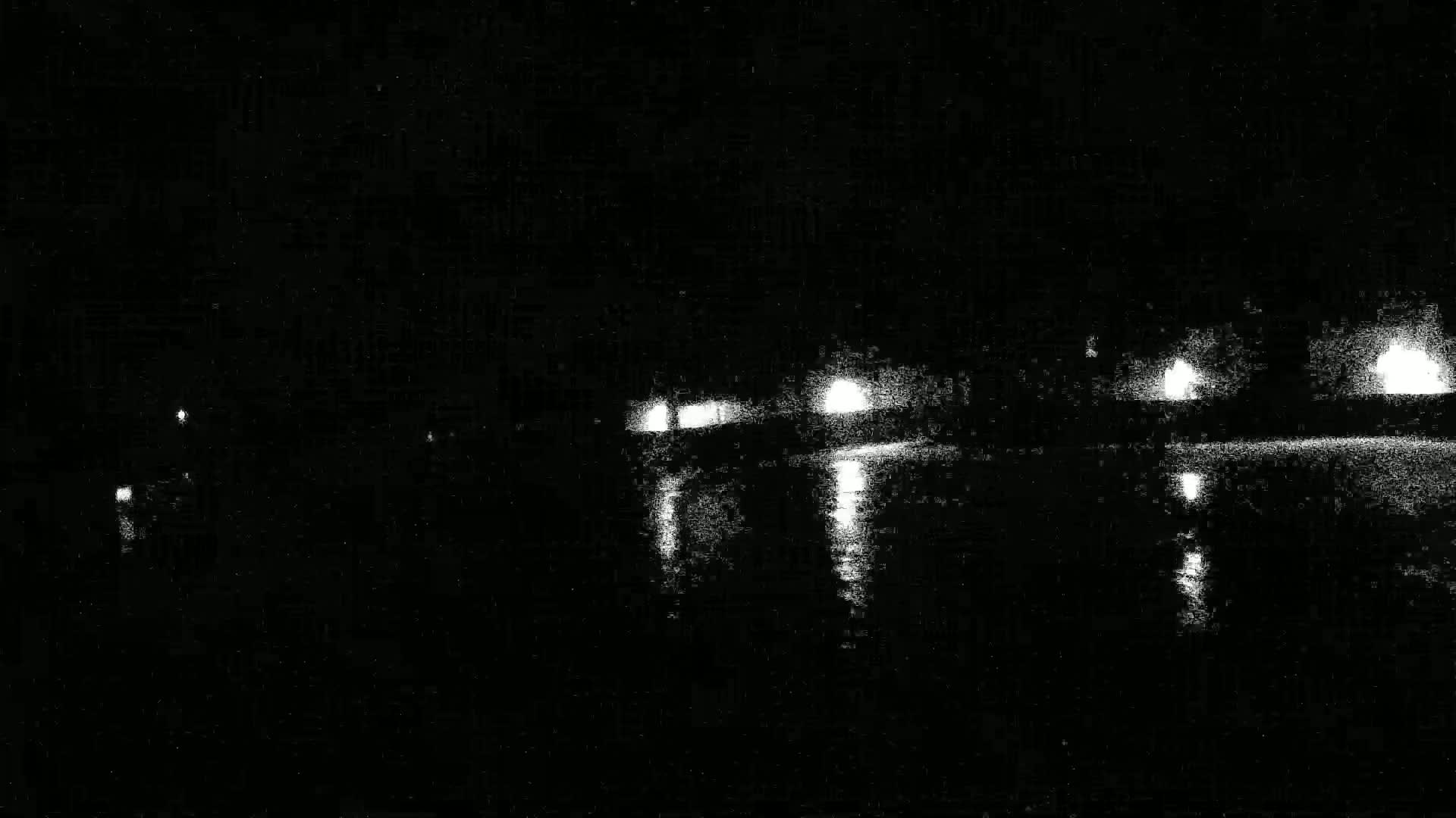 Lights from a bridge are reflected on dark water at night.