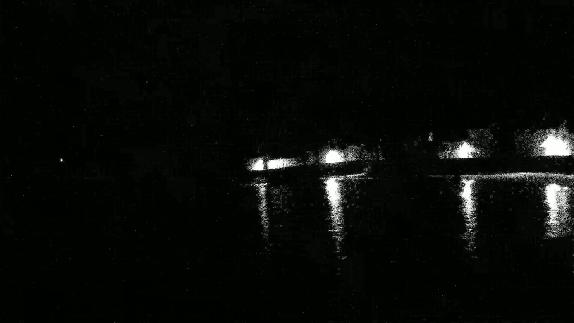 Lights from a structure are reflected on dark water at night.