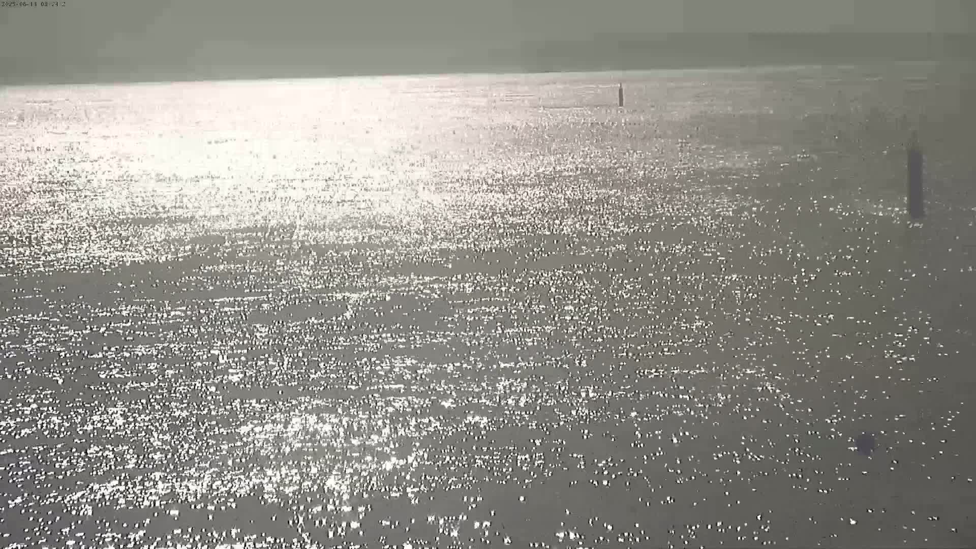 A calm body of water shimmers under a bright, overcast sky.