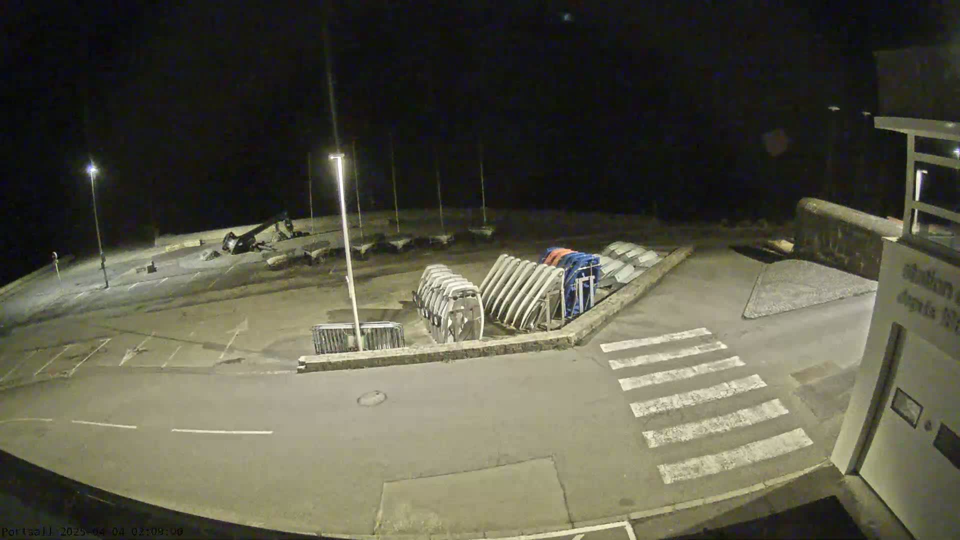 At night, a mostly empty parking lot with boat ramps and a building is illuminated by several streetlights.