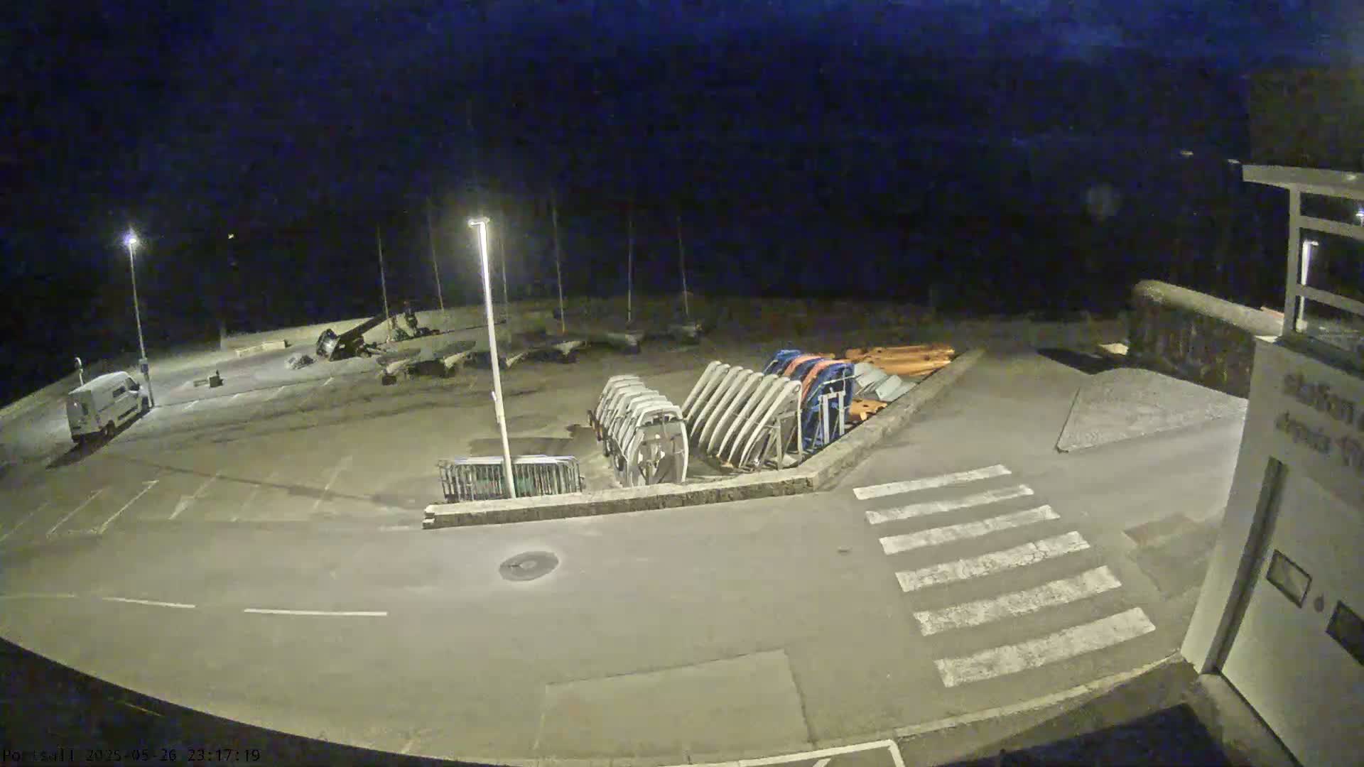 A nighttime view of an empty parking lot with several boats and a van, under a dark sky.