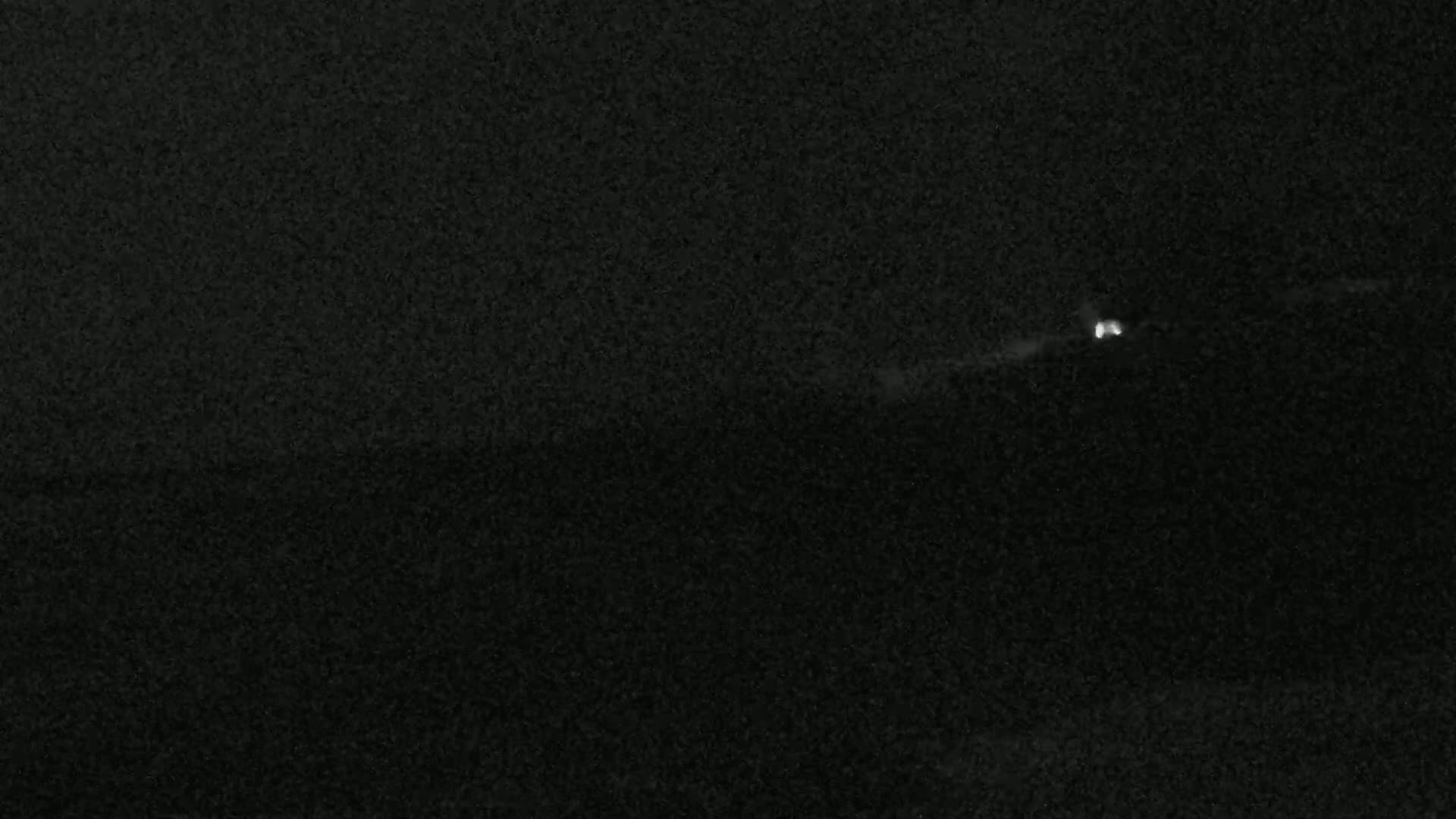 A single set of vehicle headlights are visible in the distance at night.