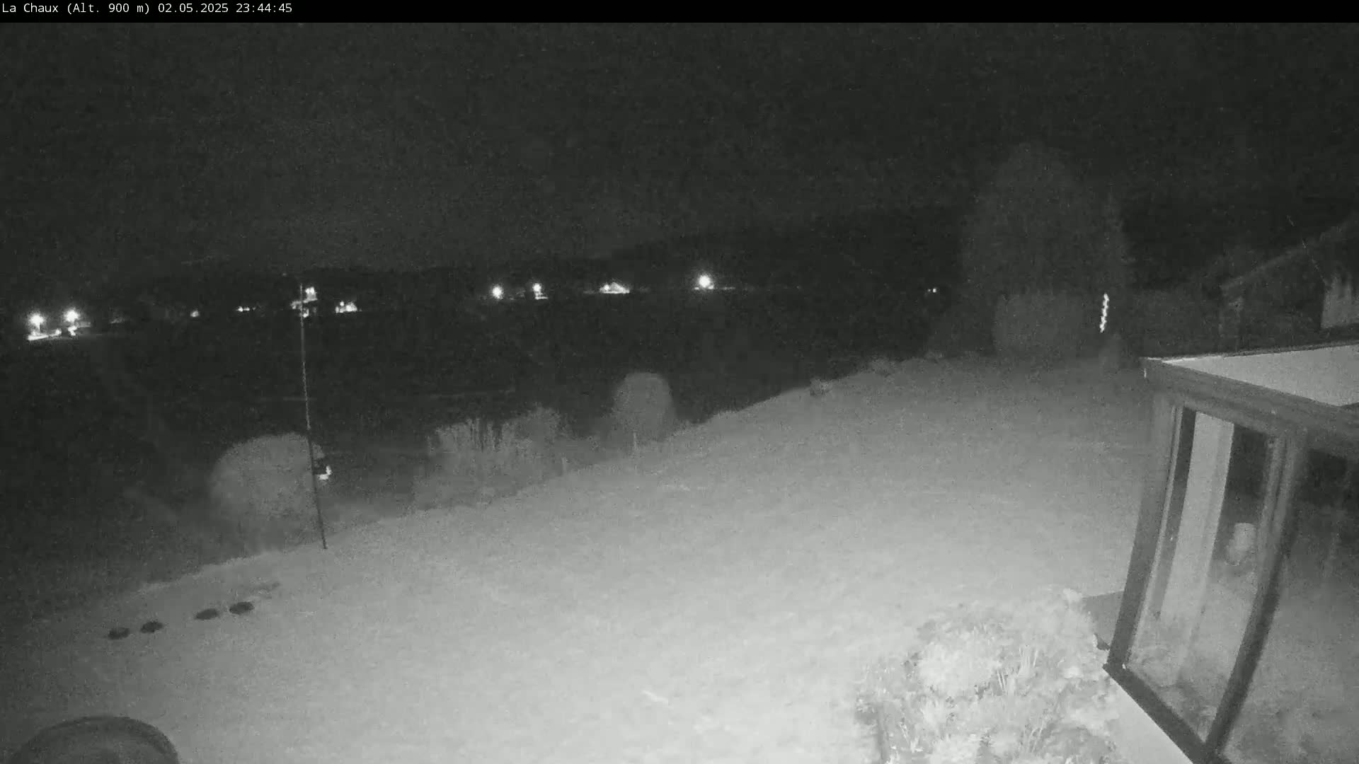 A snow-covered backyard is visible at night, with lights in the distance and a glass structure in the lower right corner.