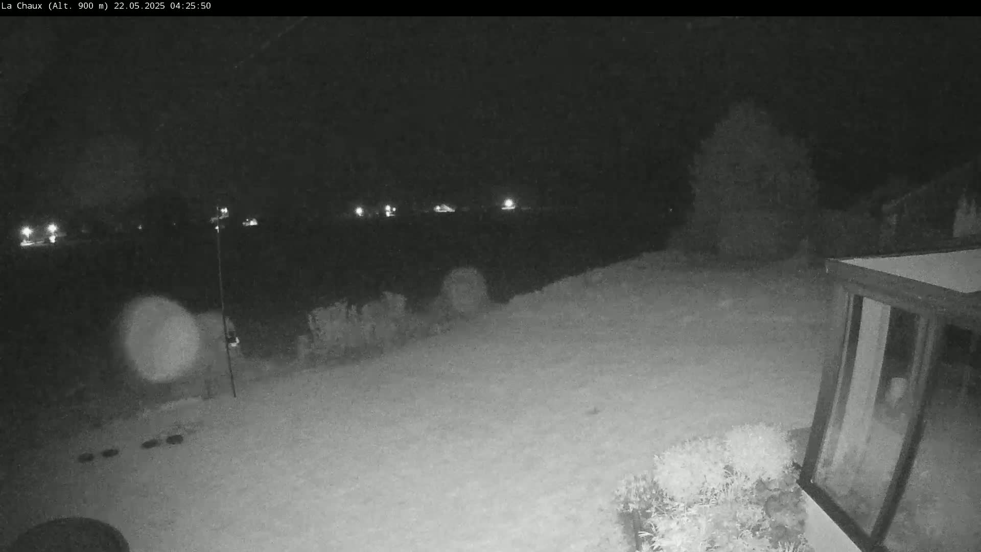 A snow-covered backyard is visible at night, with a few lights in the distance and some vegetation near a building.