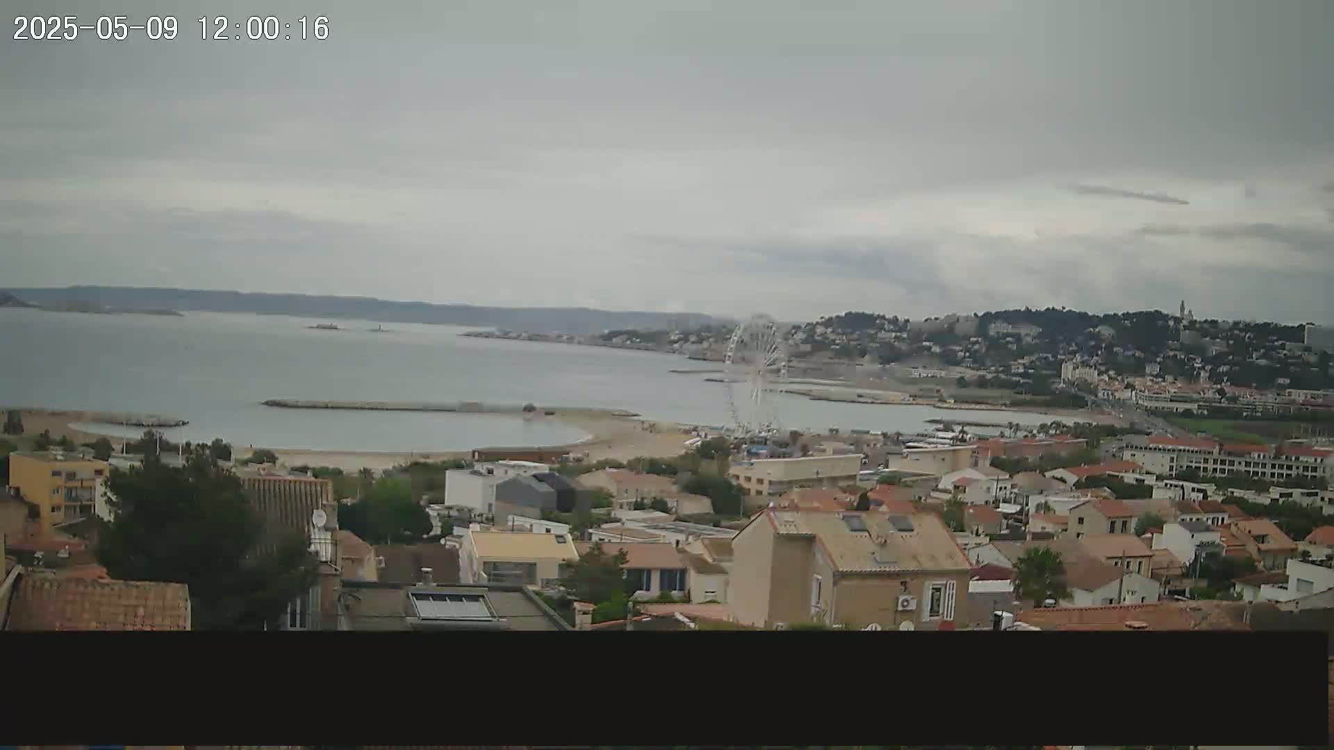 A coastal town with a Ferris wheel is visible under an overcast sky.
