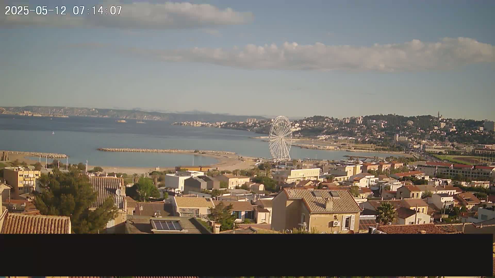 A coastal town with a Ferris wheel on the waterfront is visible under partly cloudy skies.
