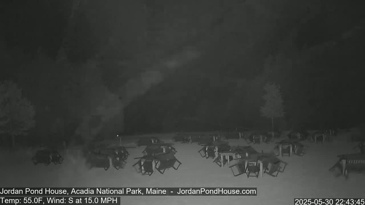 A nighttime, outdoor scene shows numerous overturned chairs and tables scattered across a snow-covered ground under a dark, cloudy sky with a 15 mph south wind and a temperature of 55°F.