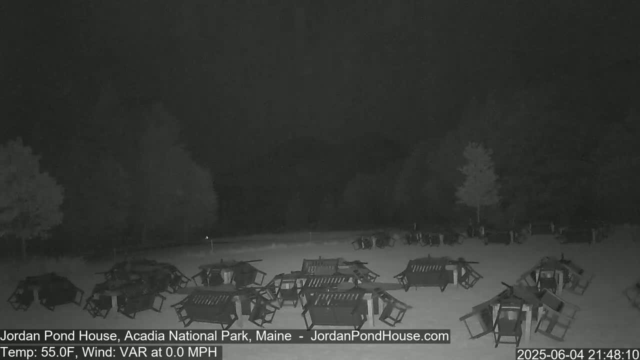 Many overturned picnic tables and chairs are scattered across a snow-covered ground at night.