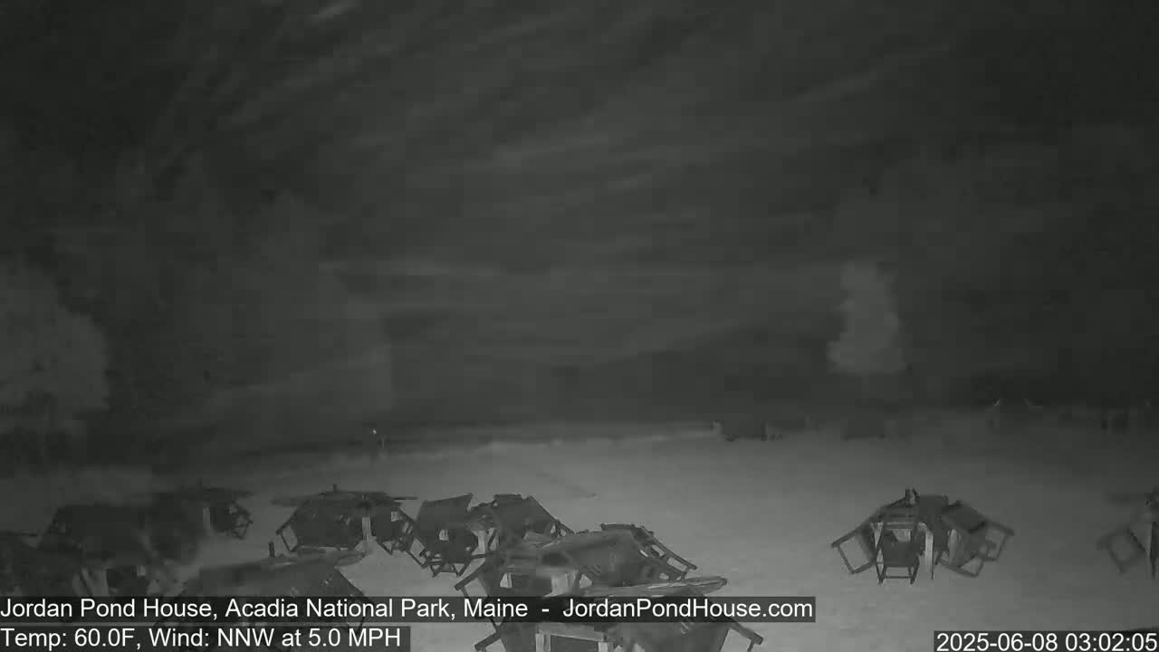 A nighttime, outdoor scene shows numerous overturned chairs scattered across a mostly empty area under a cloudy sky, with a 60°F temperature and a 5 mph north-northwest wind.