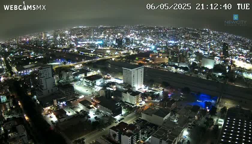 A nighttime aerial view of a sprawling city illuminated by countless lights, under a clear sky.