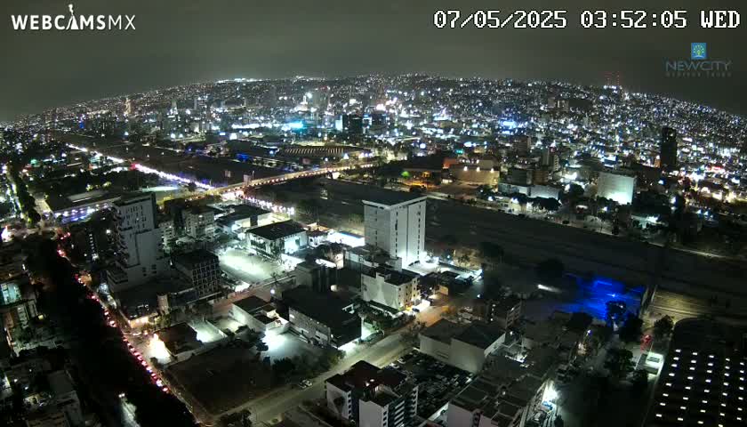 A nighttime aerial view of a sprawling city illuminated by countless lights, under a clear sky.