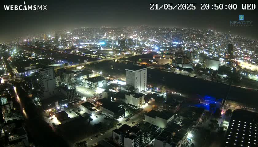 A nighttime aerial view of a brightly lit city sprawling across a dark landscape.