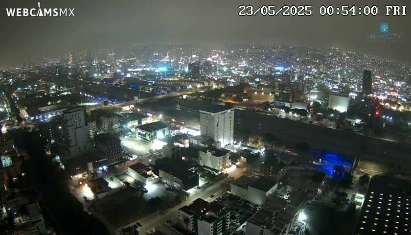 A hazy night view of a sprawling city illuminated by numerous lights, with a large highway visible in the foreground.