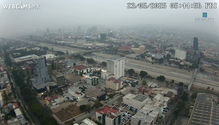 A hazy, aerial view of a city with a highway running through it, showing numerous buildings and roads.
