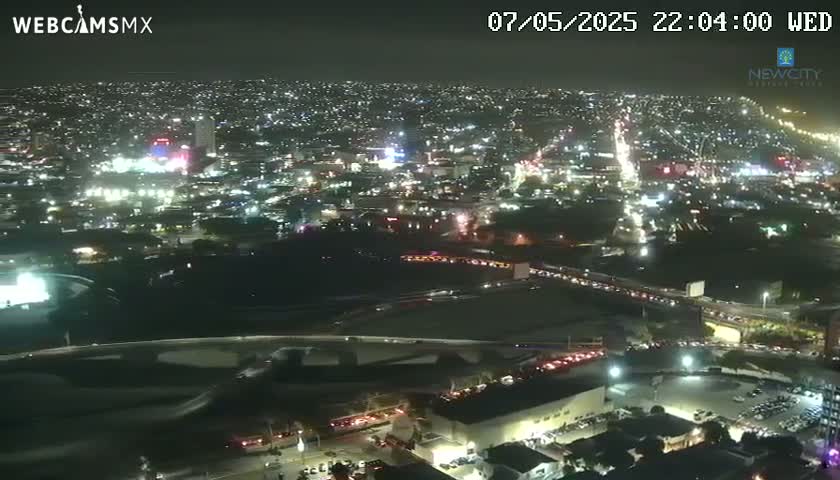 A nighttime aerial view of a city with many illuminated buildings and roads, showing heavy traffic flow.
