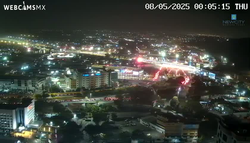 A nighttime aerial view of a brightly lit city with many buildings and roads, under clear skies.