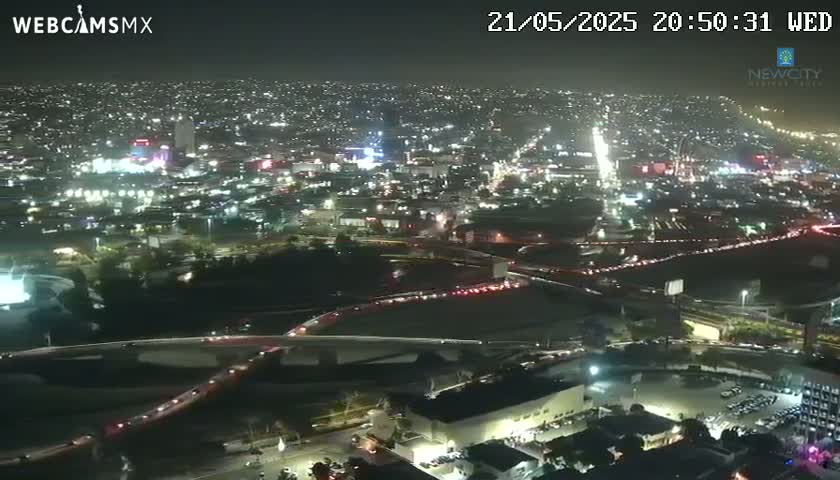 A nighttime aerial view of a city with heavy traffic congestion on roadways and illuminated buildings.