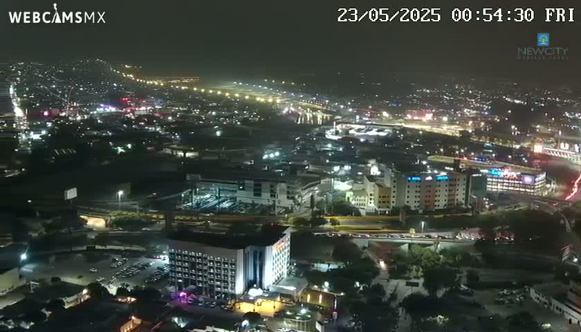 A nighttime aerial view of a city with illuminated buildings and roadways, under hazy conditions.