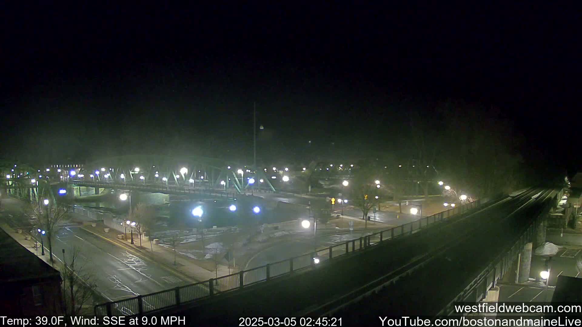 A nighttime view of a bridge and roads with minimal traffic, under a dark sky with a temperature of 39°F and a southeasterly wind at 9.0 mph.