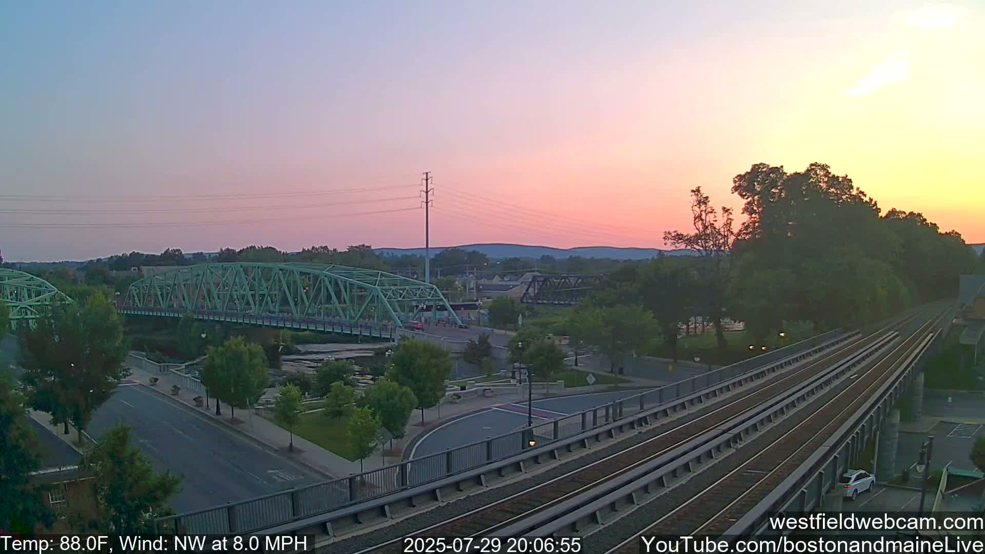A nighttime view of a bridge and roadway intersection, with calm weather conditions.