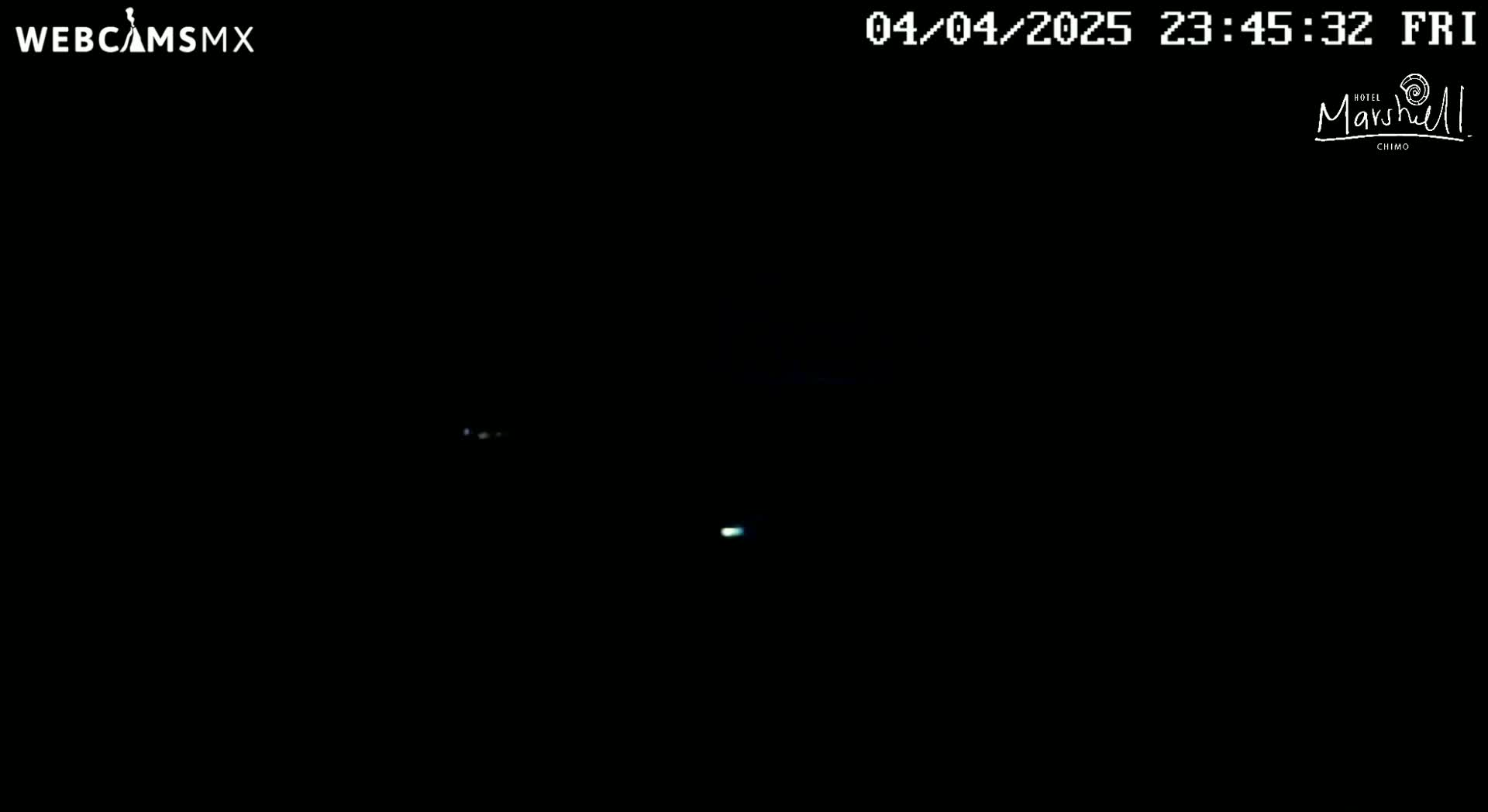 A dark nighttime scene shows a few faint lights in the distance.