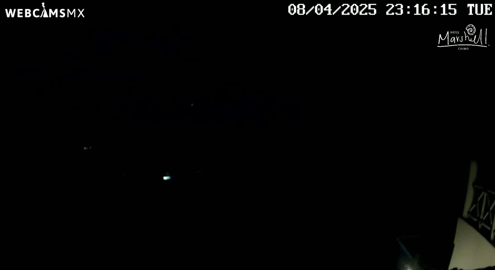A very dark image shows a few faint lights in the distance at night.