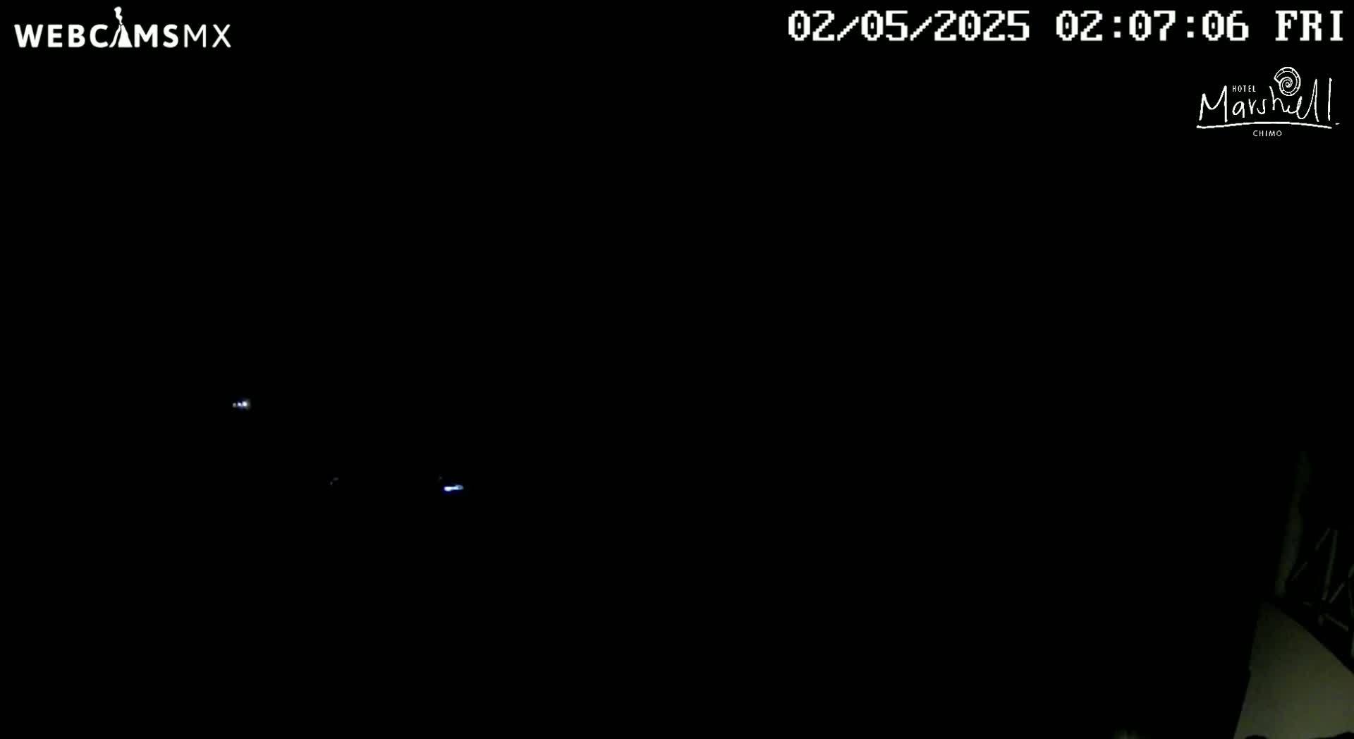 A nighttime image shows faint lights in the far distance against a completely dark background.