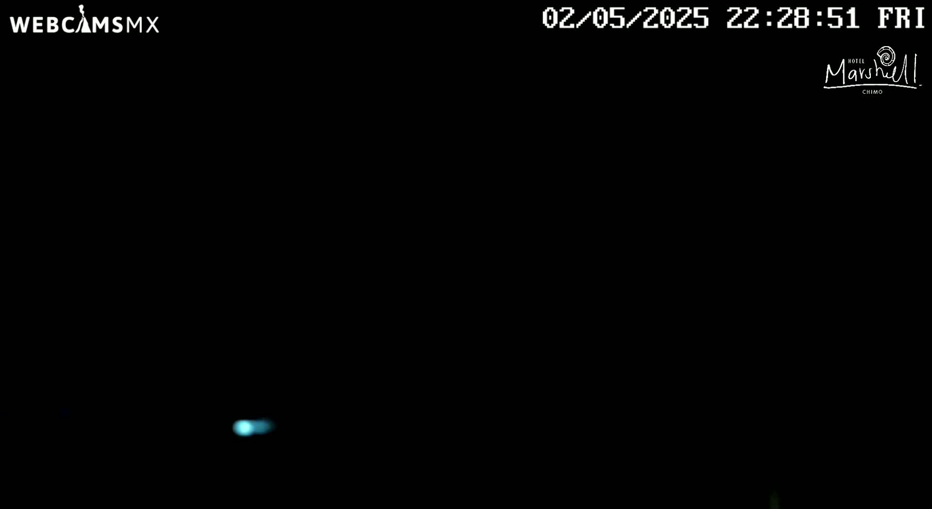 A small, faint blue light is visible in a mostly black, dark nighttime scene.