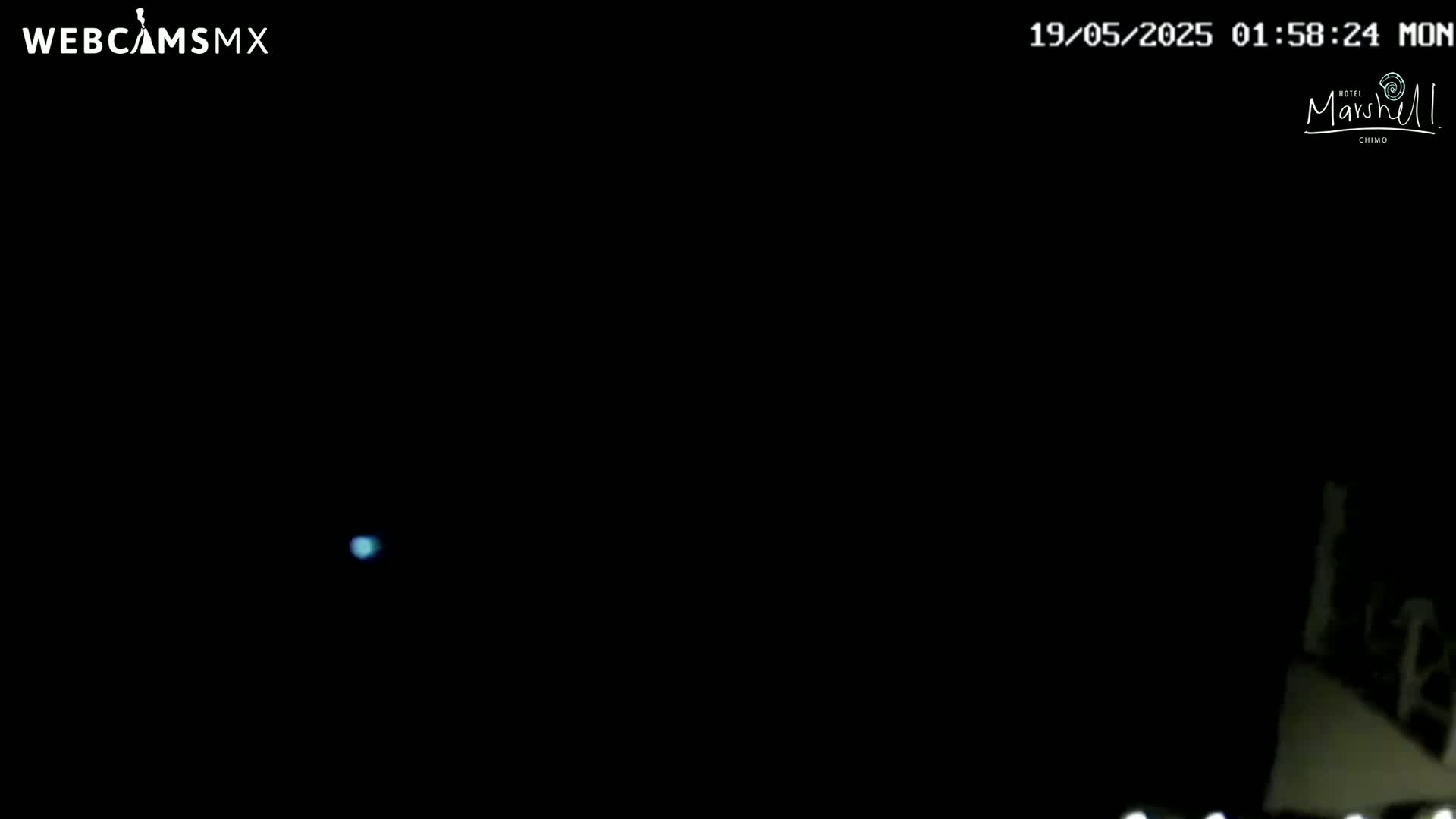 A small, faint, bluish light is visible in a predominantly dark, nighttime scene.