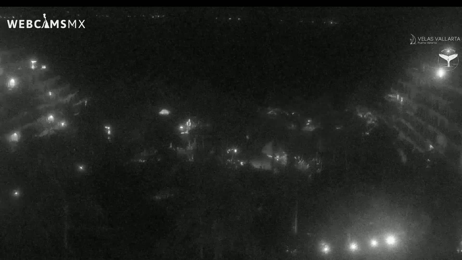 A nighttime, high-angle view shows a dark area with scattered lights, possibly a town or village, under a clear sky.