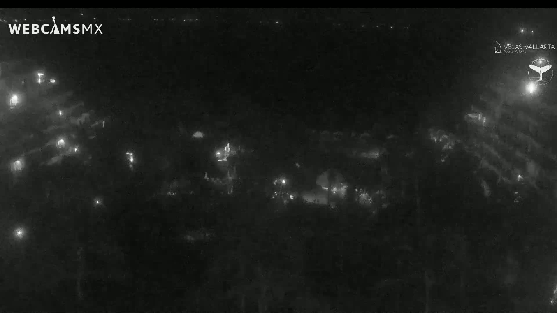 A nighttime, low-light aerial view shows a dark area with scattered small lights.