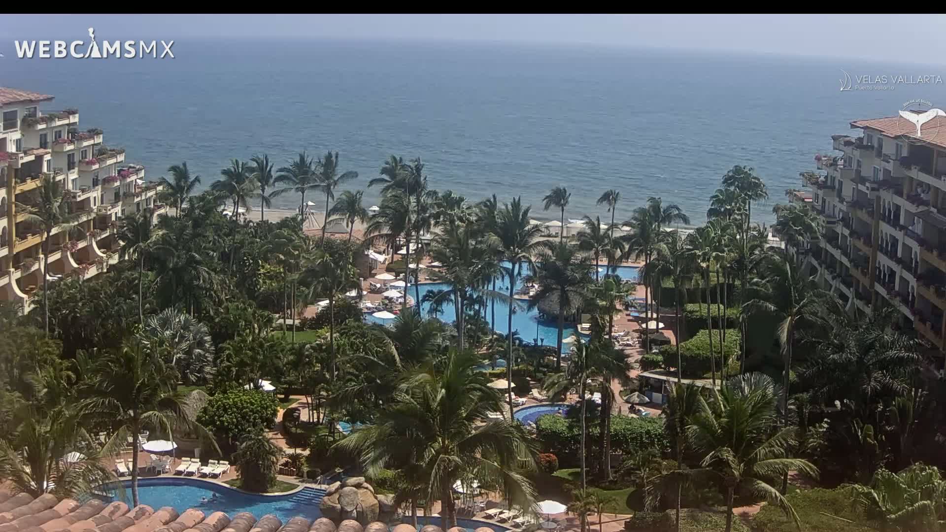 An oceanfront resort with multiple pools and palm trees is visible on a sunny day.