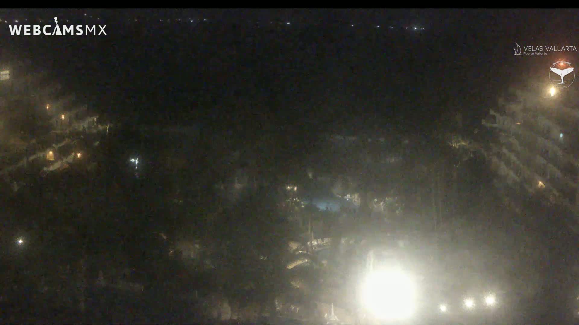 A nighttime, hazy aerial view shows a resort area with dimly lit buildings and vegetation.