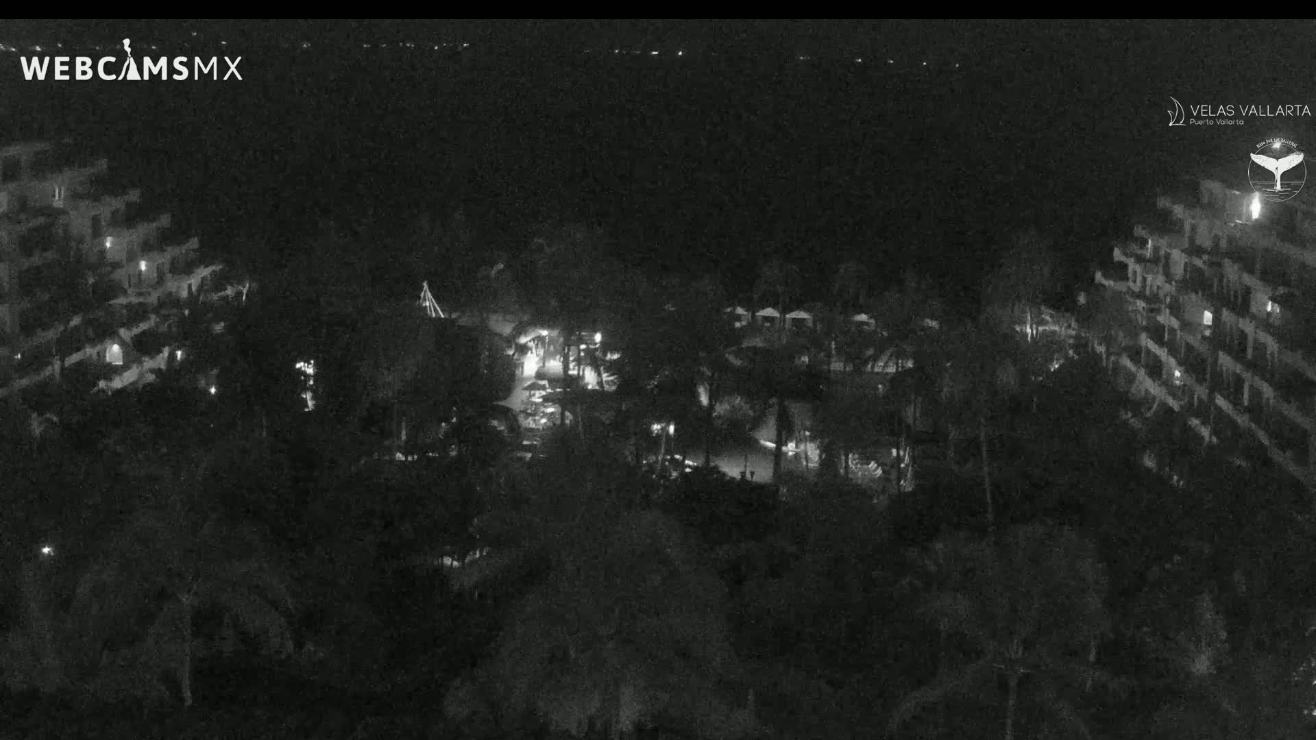 A nighttime, low-light aerial view of a resort complex with buildings, landscaping, and some lights visible.