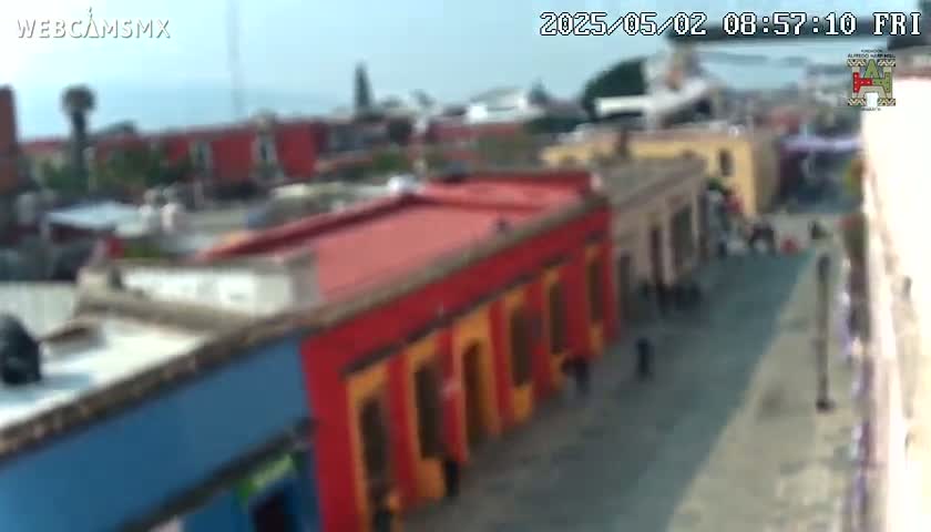 A high-angle, blurry view shows a street scene with colorful buildings under a mostly clear sky.
