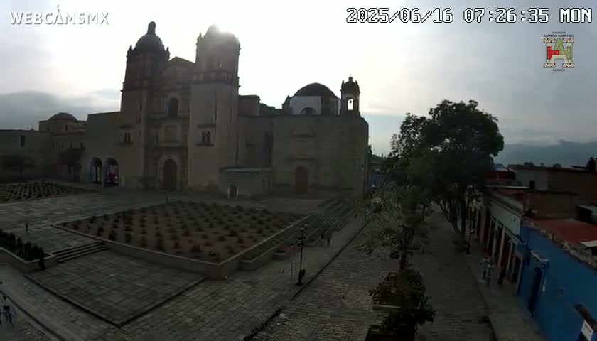 A large stone church and plaza are visible in the hazy morning light, with a cobblestone street leading away from the scene.
