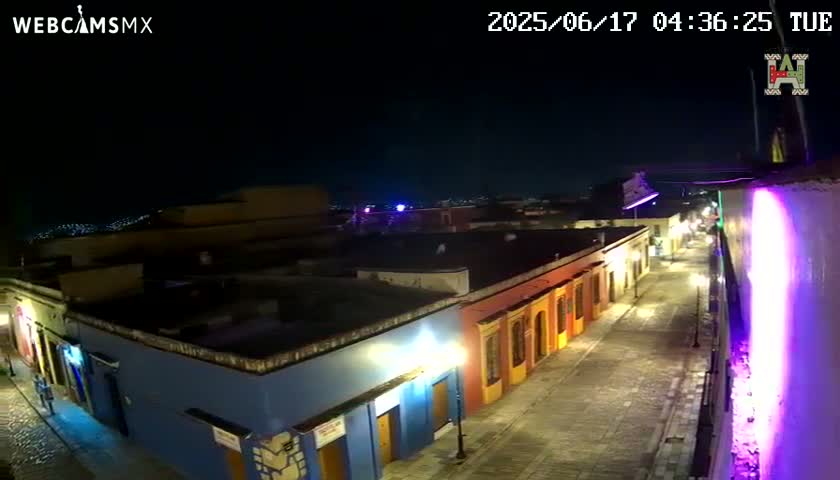 A nighttime, high-angle view of a brightly lit street lined with colorful buildings.