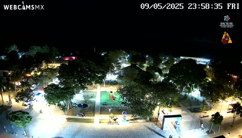 A nighttime aerial view of a park with illuminated pathways, trees, and playground equipment.
