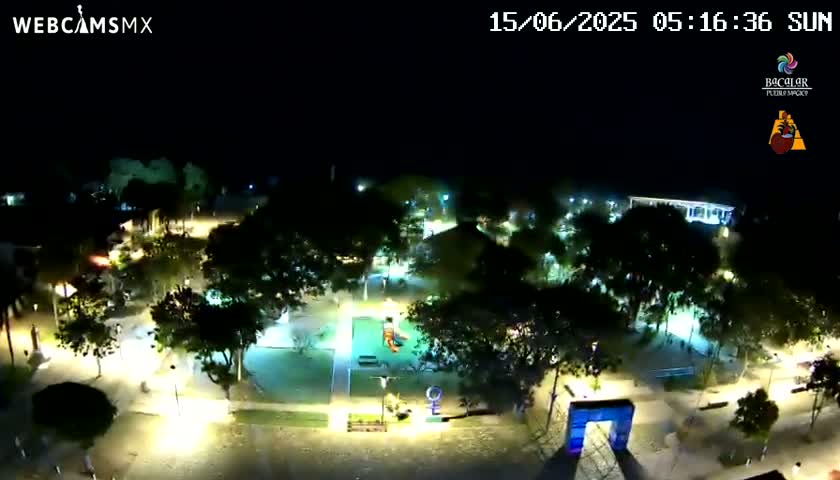 A nighttime, overhead view of a brightly lit park with trees and walkways.