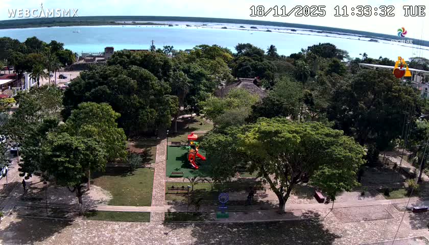 A nighttime aerial view of a town square with buildings, trees, and illuminated streets.